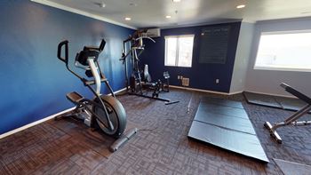 Cardio equipment against a blue accent wall in the Fitness Center of Country Meadows Apartment Homes.